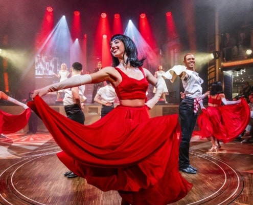 Lebendige Tanzshow auf AIDA Schiff mit Tänzern in roten Kostümen.